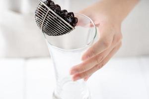 Making bubble tea, scoop and pour cooked brown sugar flavor tapioca pearl bubble balls into cup on white wooden table background, close up, copy space. photo