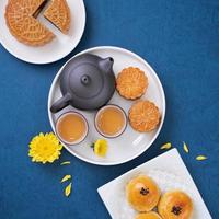 Moon cake for Mid-Autumn Festival, delicious beautiful fresh mooncake on a plate over blue background table, top view, flat lay layout design concept. photo