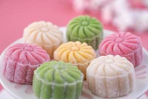 Colorful snow skin moon cake, sweet snowy mooncake, traditional savory dessert for Mid-Autumn Festival on pastel pale pink background, close up, lifestyle. photo