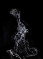 Conceptual image of white color smoke isolated on dark black background, Halloween design element concept. photo