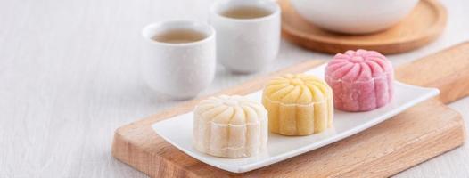 Colorful snow skin moon cake, sweet snowy mooncake, traditional savory dessert for Mid-Autumn Festival on bright wooden background, close up, lifestyle. photo