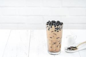 Bubble milk tea with tapioca pearl topping, famous Taiwanese drink on white wooden table background in drinking glass, close up, copy space photo