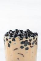 Bubble milk tea with tapioca pearl topping, famous Taiwanese drink on white wooden table background in drinking glass, close up, copy space photo