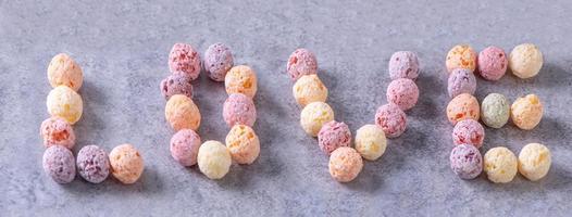 mezcla de bolas de maíz de cereales de colores, dulces de cuenco de sabor a fruta sobre fondo de cemento gris, primer plano, desayuno fresco, delicioso y saludable, concepto de diseño de espacio de copia. foto