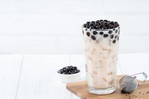 Bubble milk tea with tapioca pearl topping, famous Taiwanese drink on white wooden table background in drinking glass, close up, copy space photo