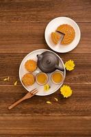 Moon cake for Mid-Autumn Festival, delicious beautiful fresh mooncake on a plate over dark wooden background table, top view, flat lay layout design concept. photo