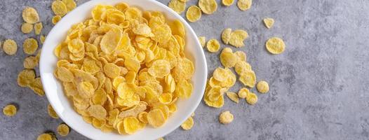 Corn flakes bowl sweets on gray cement background, top view flat lay layout design, fresh and healthy breakfast concept. photo