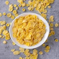 Corn flakes bowl sweets on gray cement background, top view flat lay layout design, fresh and healthy breakfast concept. photo