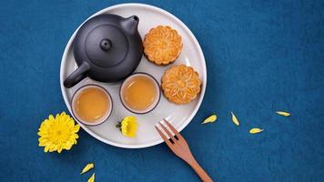 Moon cake for Mid-Autumn Festival, delicious beautiful fresh mooncake on a plate over blue background table, top view, flat lay layout design concept. photo