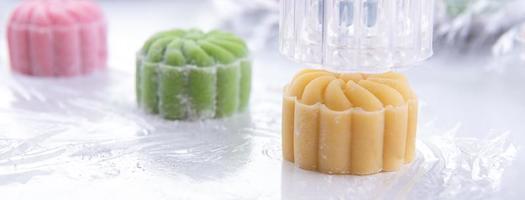 Young woman is making colorful snow skin moon cake, recipe of sweet snowy mooncake, traditional savory dessert for Mid-Autumn Festival, close up, lifestyle. photo