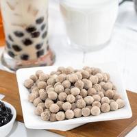 Bubble milk tea with tapioca pearl topping ingredient, famous Taiwanese drink on white wooden table background in drinking glass, close up, copy space photo