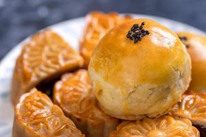 Tasty baked egg yolk pastry moon cake for Mid-Autumn Festival on black slate dark background. Chinese festive food concept, close up, copy space. photo