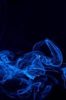 Conceptual image of blue color smoke isolated on dark black background, Halloween design element concept. photo