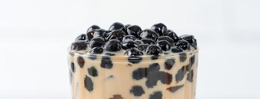 Bubble milk tea with tapioca pearl topping, famous Taiwanese drink on white wooden table background in drinking glass, close up, copy space photo