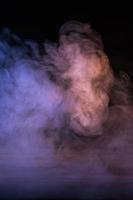 imagen conceptual de humo multicolor aislado sobre fondo negro oscuro y mesa de madera. foto