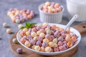 Colorful cereal corn balls mix, fruit flavor bowl sweets on gray cement background, close up, fresh, delicious and healthy breakfast, copy space design concept. photo