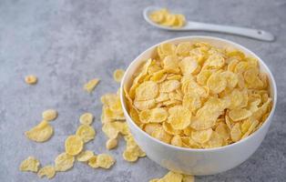 Corn flakes bowl sweeties with milk on gray cement background, close up, fresh and healthy breakfast design concept. photo