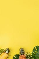 hermosa piña en hojas de monstera de palma tropical aisladas sobre fondo amarillo pastel brillante, vista superior, puesta plana, sobre la fruta de verano. foto