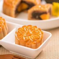 Tasty baked egg yolk pastry moon cake for Mid-Autumn Festival on bright wooden table background. Chinese festive food concept, close up, copy space. photo