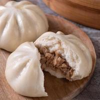 Delicious baozi, Chinese steamed meat bun is ready to eat on serving plate and steamer, close up, copy space product design concept. photo