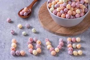 mezcla de bolas de maíz de cereales de colores, dulces de cuenco de sabor a fruta sobre fondo de cemento gris, primer plano, desayuno fresco, delicioso y saludable, concepto de diseño de espacio de copia. foto