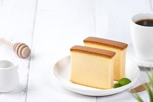 castella kasutera - hermosa y deliciosa comida japonesa de bizcocho en rodajas en un plato blanco sobre una mesa rústica de madera blanca, primer plano, concepto de diseño de espacio de copia. foto