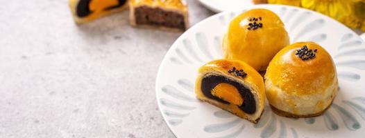 Tasty baked egg yolk pastry moon cake for Mid-Autumn Festival on bright cement table background. Chinese traditional food concept, close up, copy space. photo