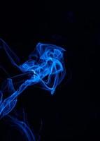imagen conceptual de humo de color azul aislado sobre fondo negro oscuro, elemento de diseño de concepto de halloween. foto