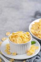 Corn flakes bowl sweeties with milk on gray cement background, close up, fresh and healthy breakfast design concept. photo