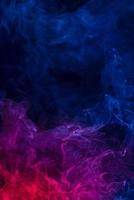 Conceptual image of multi-colored smoke isolated on dark black background, Halloween design element. photo