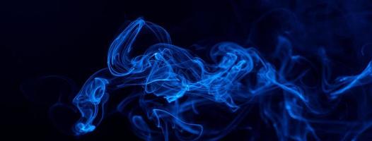 Conceptual image of blue color smoke isolated on dark black background, Halloween design element concept. photo