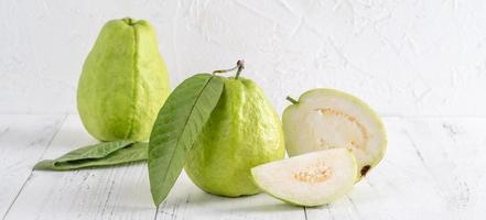 Delicious beautiful Guava set with fresh leaves isolated on bright white wooden table background, close up. photo