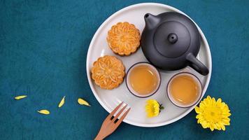 Moon cake for Mid-Autumn Festival, delicious beautiful fresh mooncake on a plate over blue background table, top view, flat lay layout design concept. photo