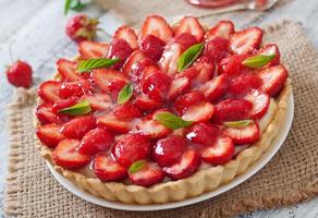 Tart with strawberries and whipped cream decorated with mint leaves photo