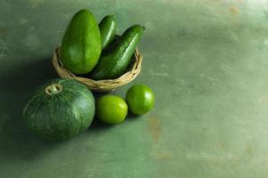 Green fruit avocado pumpkin and green lemon on wood table close up. photo