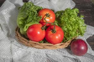 Ensalada de alimentos saludables lechuga tomate en cesta y maracuyá sobre fondo de madera. foto