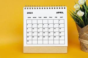 White April 2023 calendar with potted plant on yellow background. photo