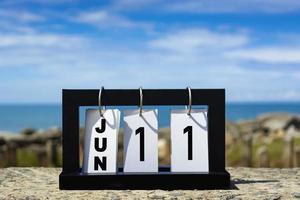 Jun 11 calendar date text on wooden frame with blurred background of ocean. photo