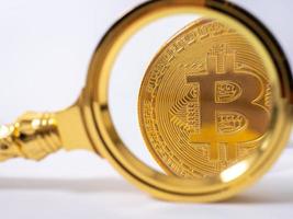 Golden bitcoin magnifying glass on a blurred background of coins photo