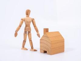 Man leaned against the model of a house isolated on white background. Concept with a wooden puppet photo