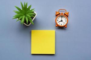 Adhesive Note with potted plant and alarm clock set at 8 o'clock. Copy space. photo