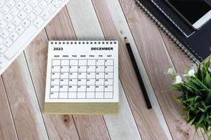 White December 2023 desk calendar on wooden desk. Directly above. Flat lay. photo