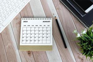blanco agosto 2023 calendario de escritorio en escritorio de madera. directamente arriba. endecha plana foto