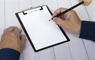 Hand with pencil writing something on the black clipboard. Copy space. photo