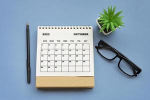 October 2023 desk calendar on blue background. Directly above. Flat lay. photo