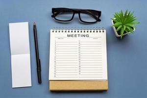 Meeting timetable calendar with notepad on blue background. Business concept. photo