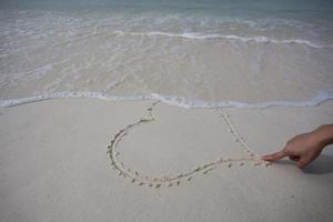 corazones dibujados en la arena de una playa foto