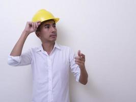 engineer with hands crossed wearing yellow helmet on white background photo