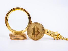 réplica de bitcoin dorado y lupa sobre fondo blanco.concepto de negocios y finanzas. foto