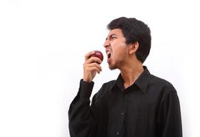 Young healthy man eating a red apple photo